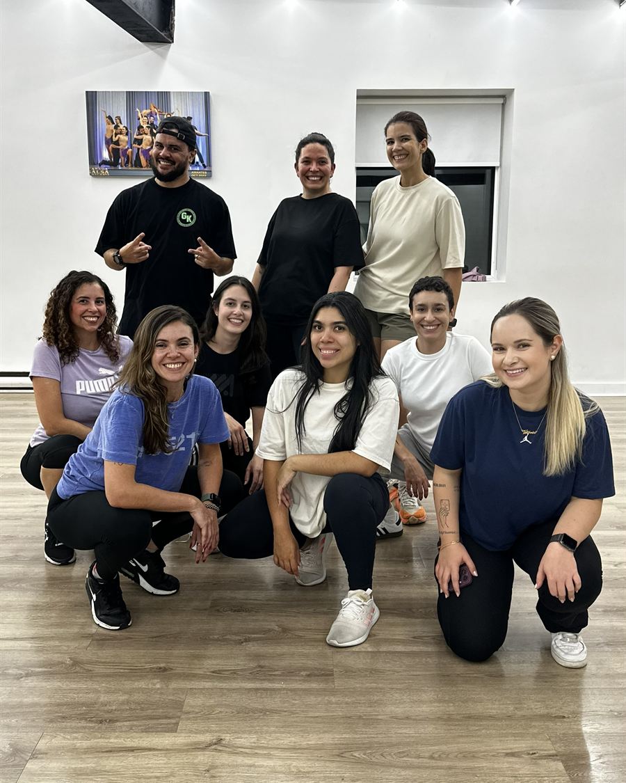 Alunos da Brasileirada de diferentes idades e estilos agachados juntos e sorrindo depois da aula